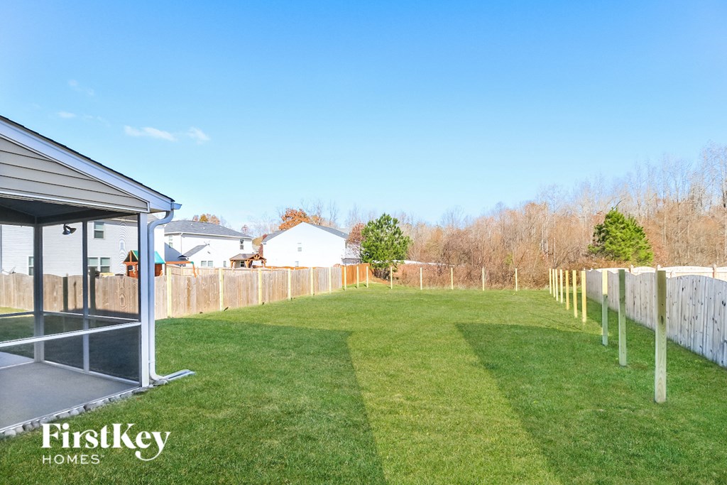 a backyard with a fence and a grass lawn and a house