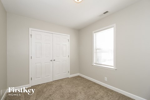a bedroom with a closet and a window and a white door