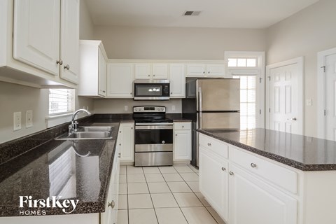 A kitchen with white cabinets and a black counter top.