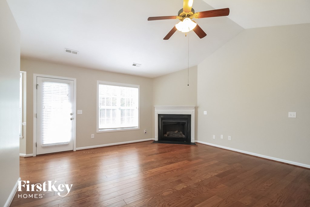 an empty living room with a ceiling fan and a fireplace