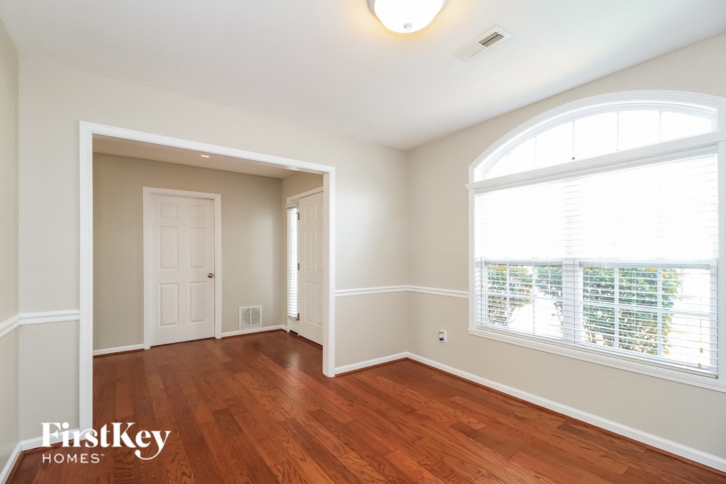 an empty living room with a large window and wood flooring