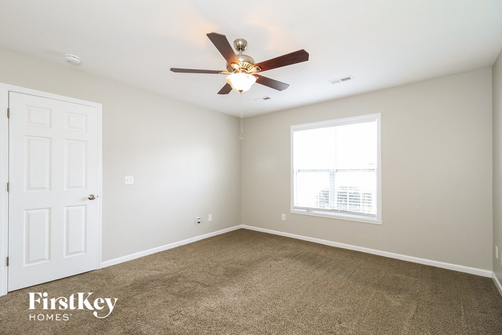 a carpeted room with a ceiling fan and a window