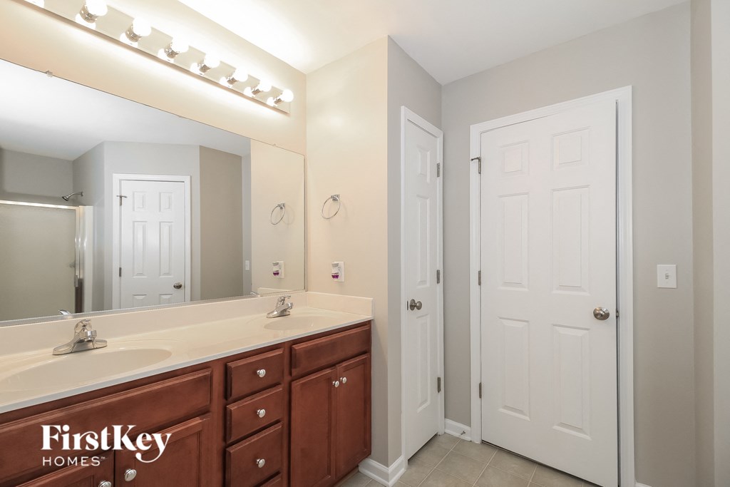 a bathroom with a sink and a mirror and a door to a closet