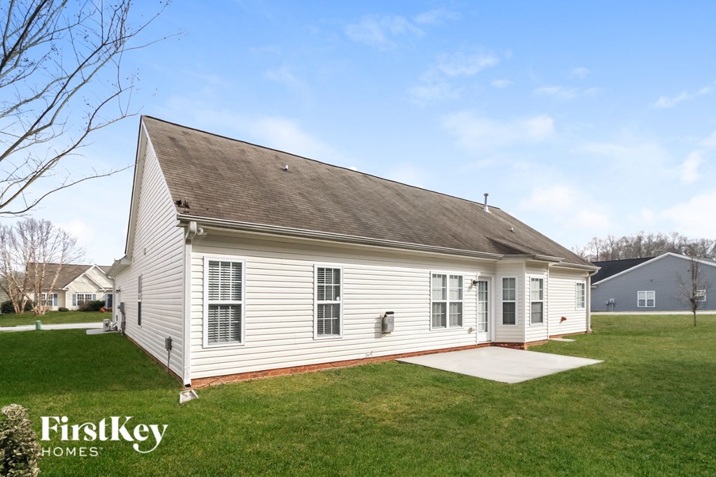 the front of a white house with a yard and a driveway