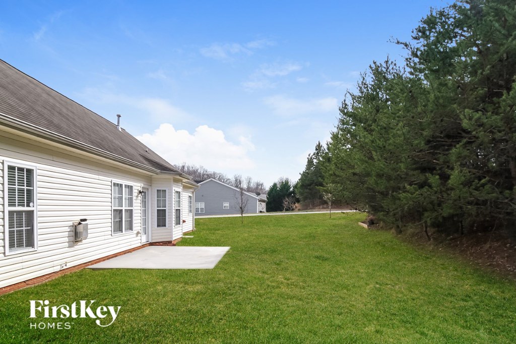 a backyard with a lawn and a white house