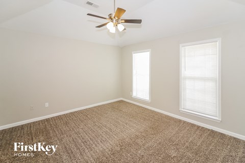 the spacious living room with carpet and a ceiling fan