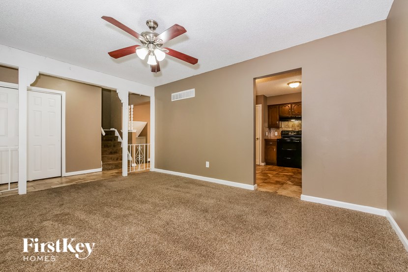 A spacious room with a carpeted floor and a ceiling fan.