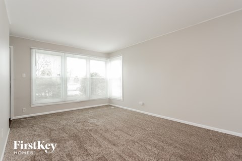a spacious living room with carpet and large windows