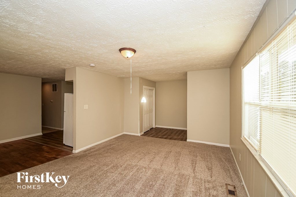 A spacious room with a carpeted floor and a light hanging from the ceiling.