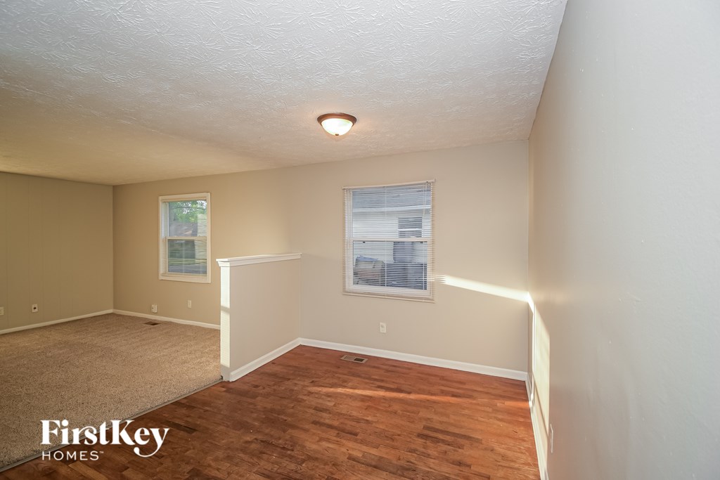 A room with a carpeted floor and a window with blinds.