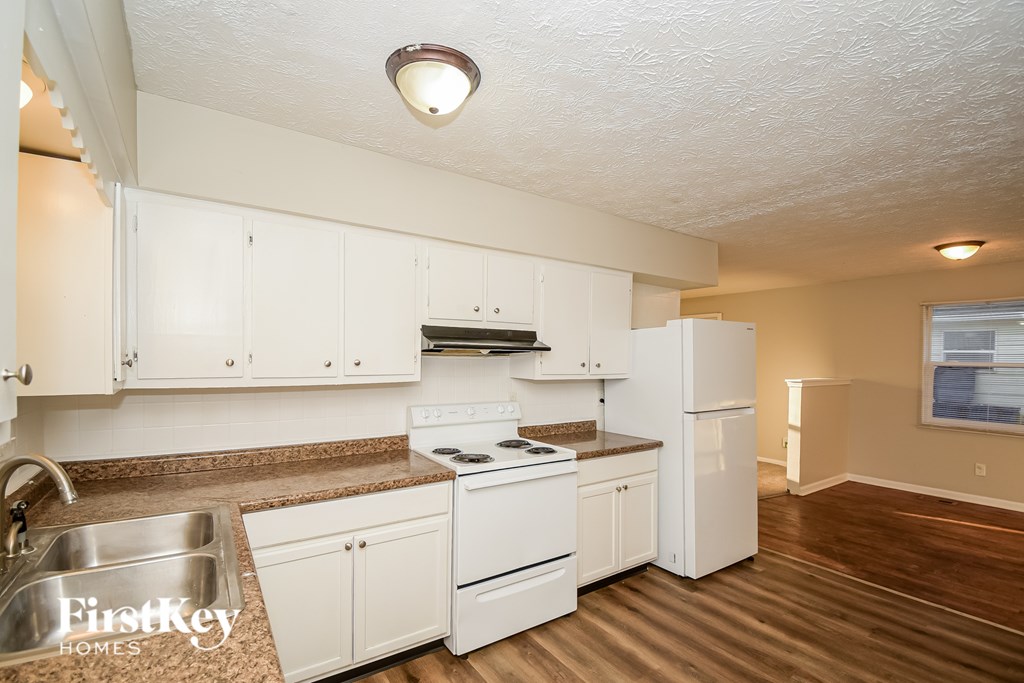 A kitchen with white cabinets and a stove top oven.