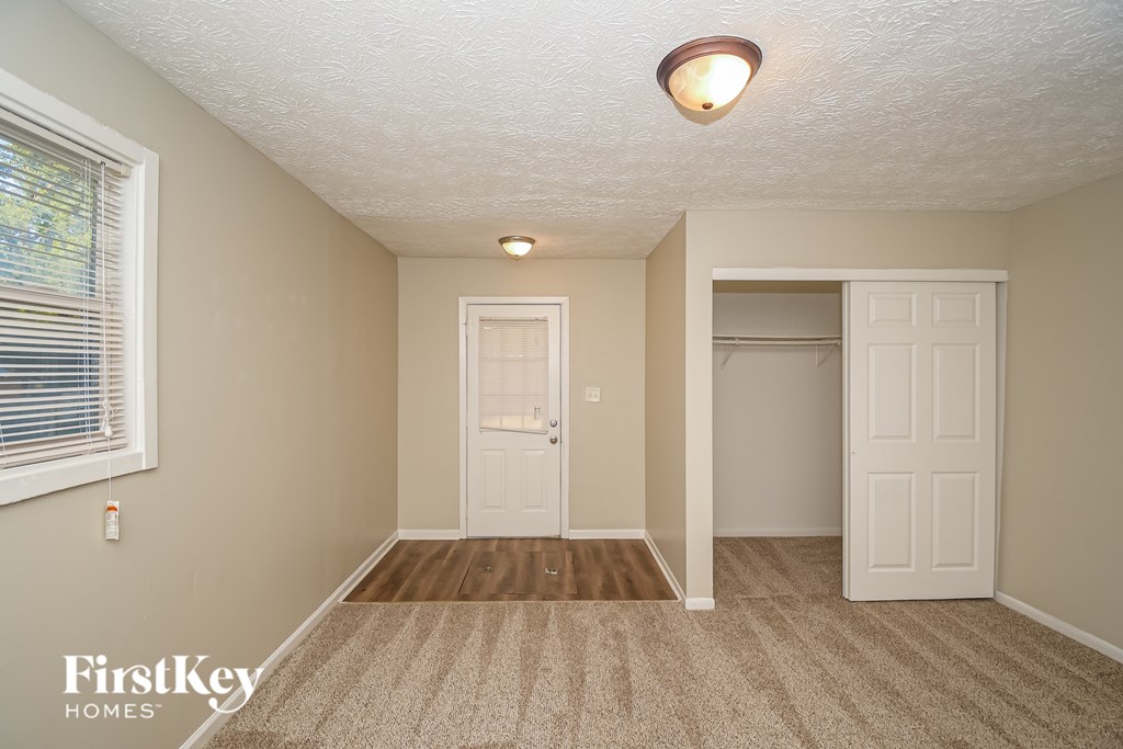 A room with a carpeted floor and two doors.