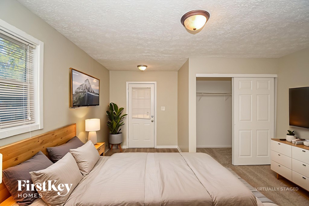 A bedroom with a bed, dresser, and a painting on the wall.