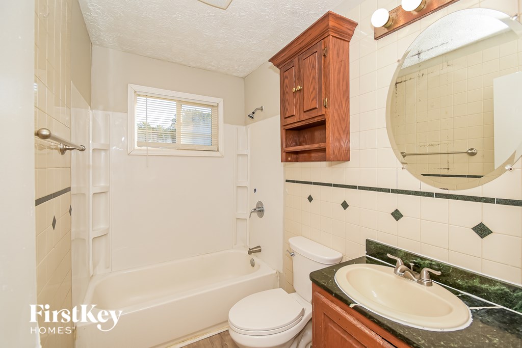 A bathroom with a white tub, toilet, and sink.
