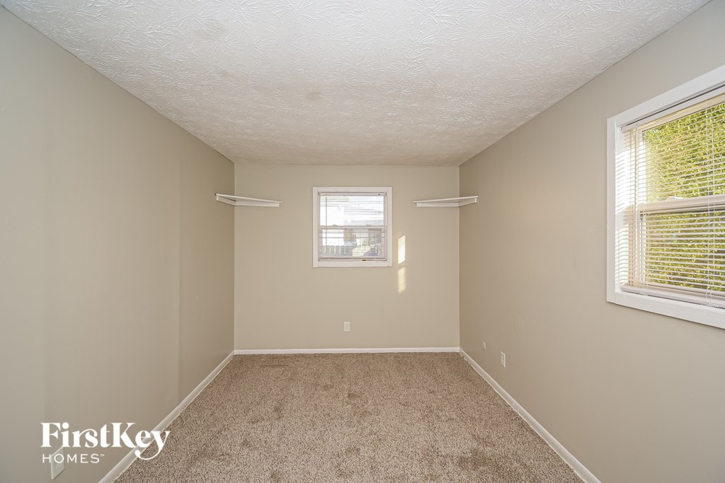 A room with a window and a carpeted floor.
