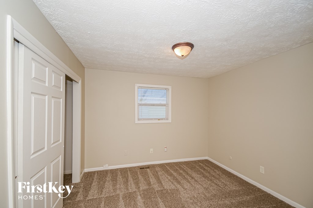 A room with a carpeted floor and a window with a white frame.