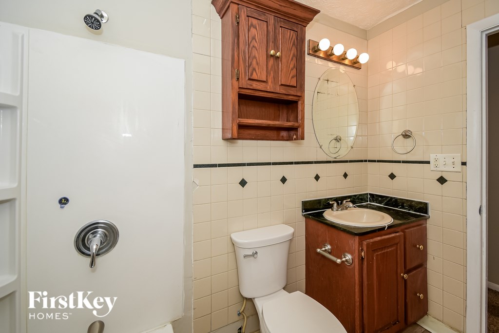 A bathroom with a toilet, sink, and wooden cabinet.