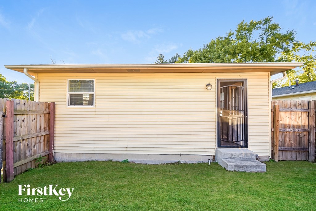 A small house with a wooden fence in front of it.