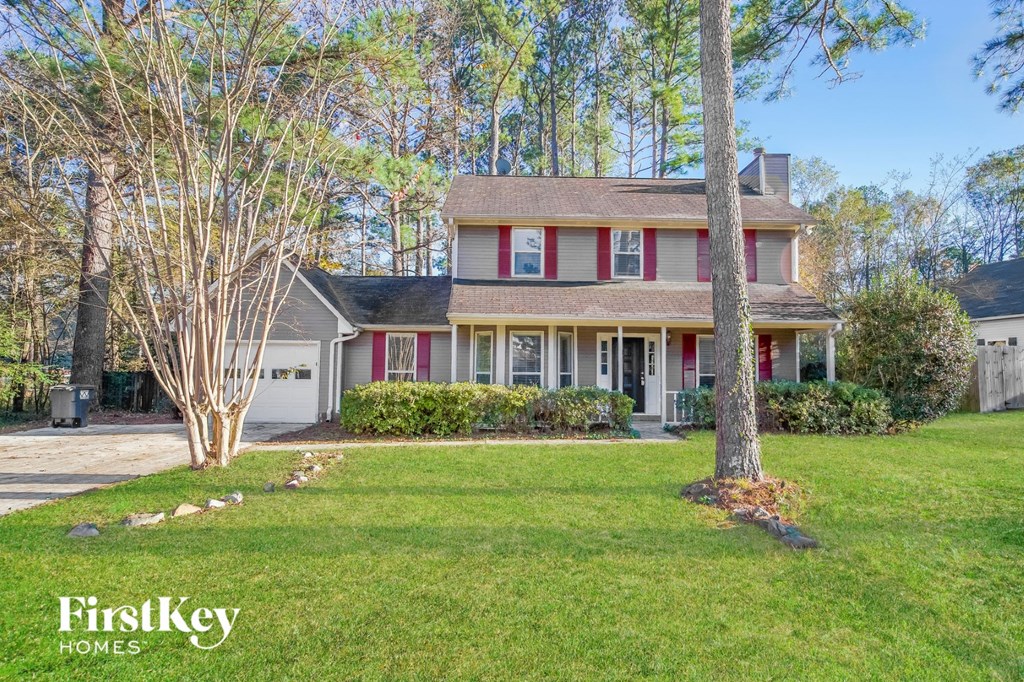 a house with red shutters and a lawn and a tree