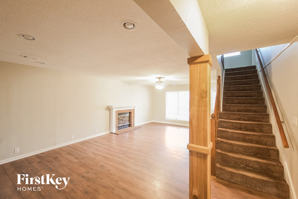 an empty living room with a staircase and wood flooring