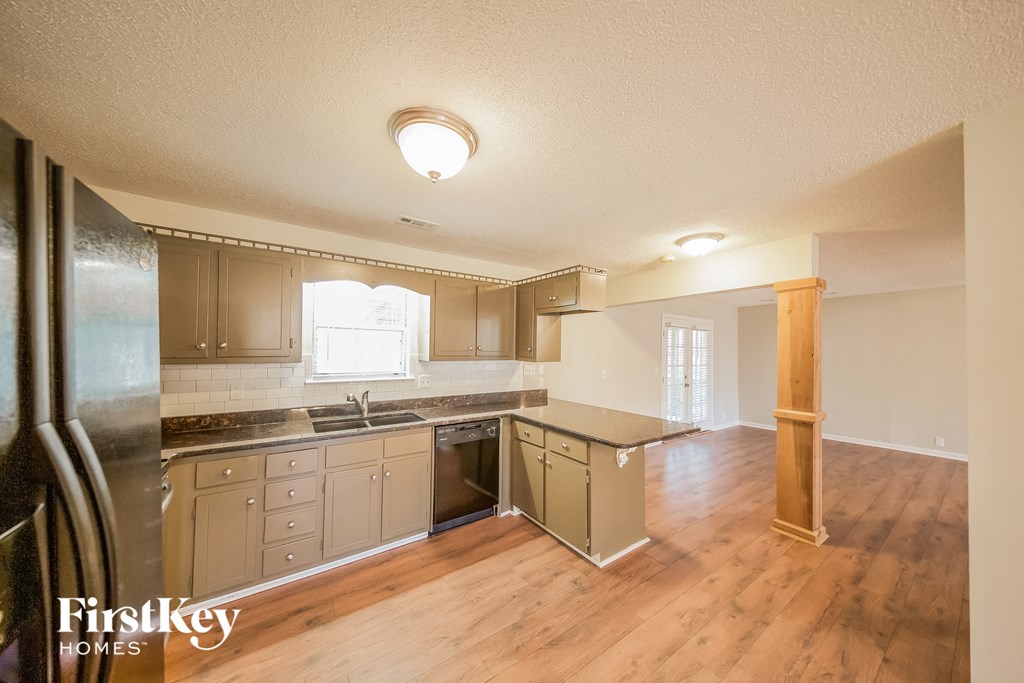 an empty kitchen with stainless steel appliances and wood flooring