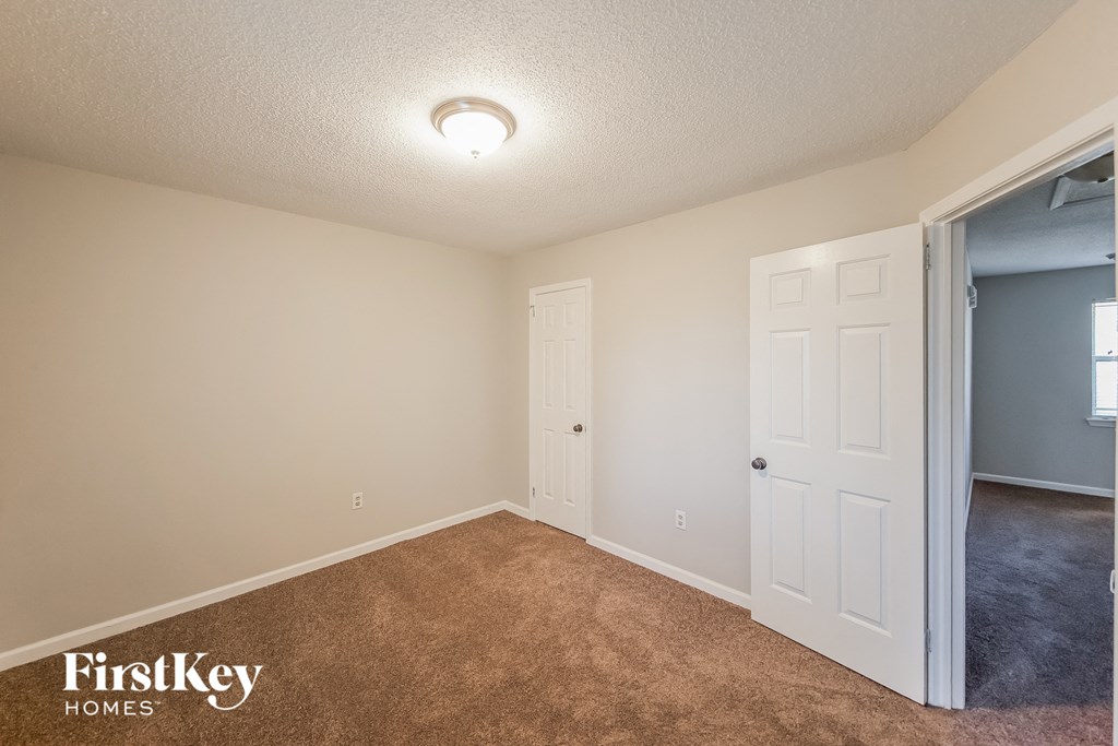 a bedroom with a door to a closet and a carpeted floor
