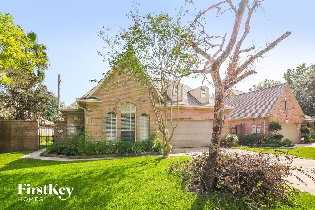 front view of a brick house with a yard and a tree
