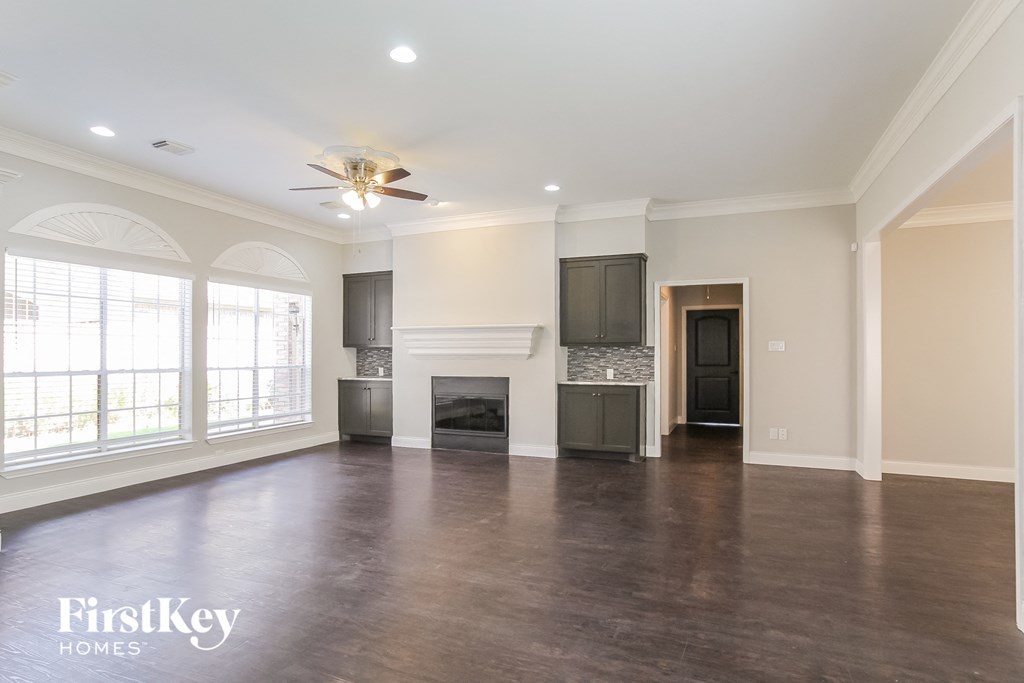 an empty living room with a fireplace and a ceiling fan