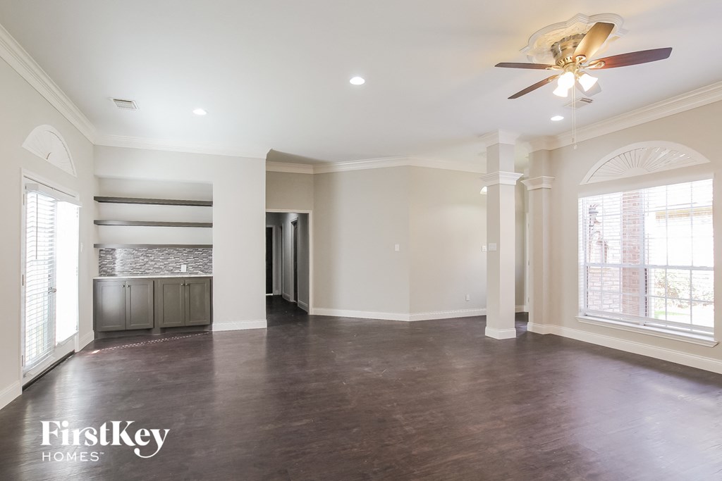 an empty living room with a ceiling fan