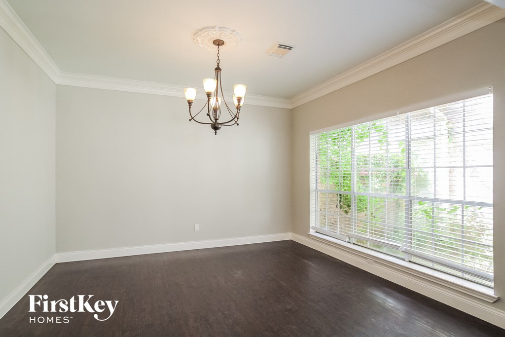a empty dining room with a large window and a chandelier