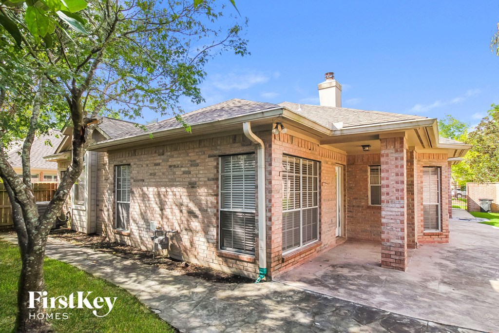a brick house with a driveway and a tree