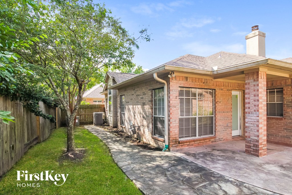 a brick house with a sidewalk and a tree