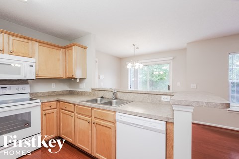 A kitchen with wooden cabinets and a white dishwasher.