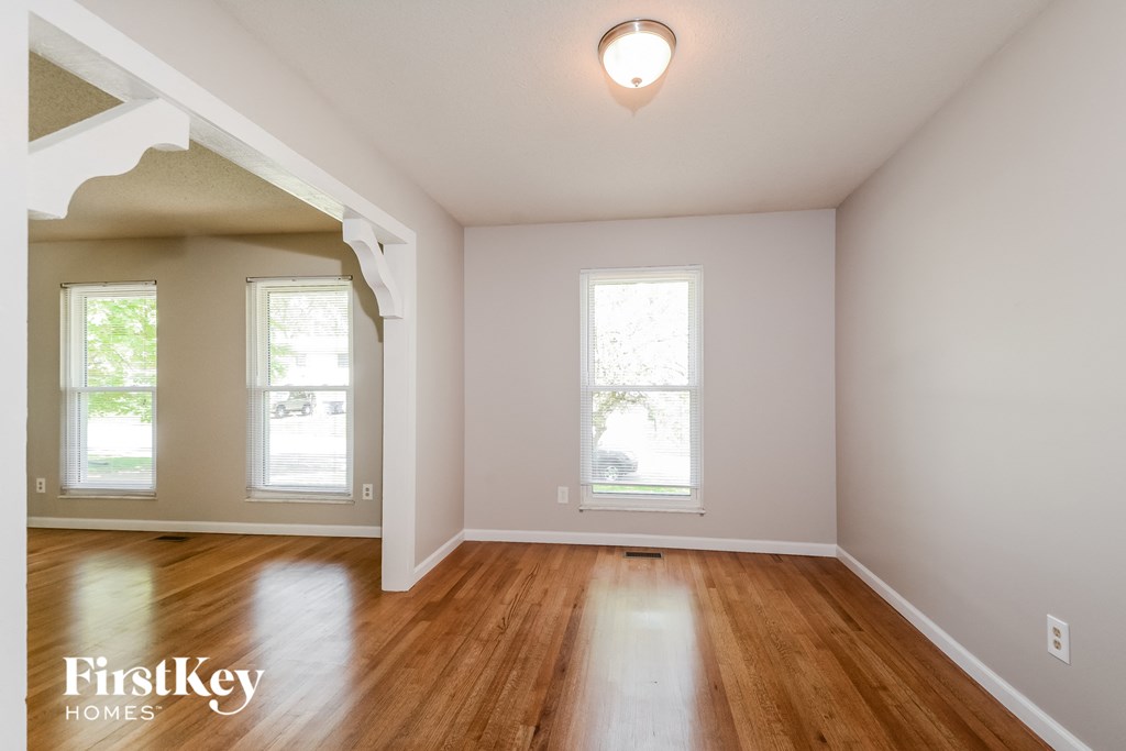 an empty living room with hardwood floors and two windows