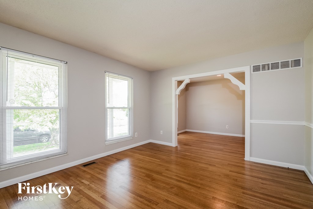 a living room with a hardwood floor and a door way to an empty room