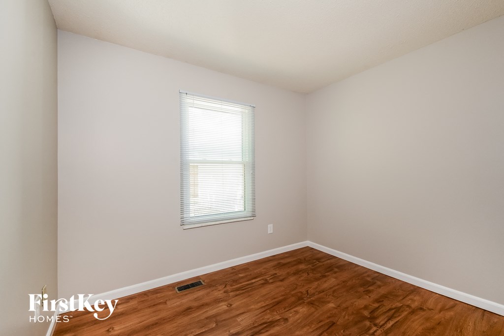 a bedroom with wood floors and white walls and a window