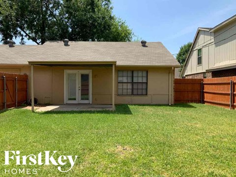 A house with a brown fence and a green lawn.