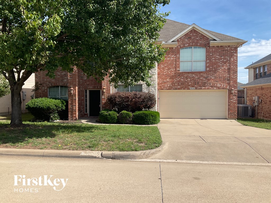 a house with a driveway and a tree in front of it