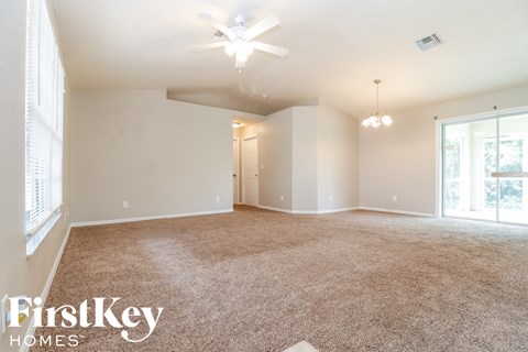 a spacious living room with carpet and a ceiling fan