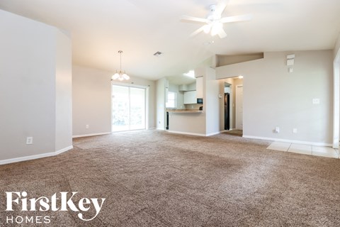an empty living room with carpet and a ceiling fan