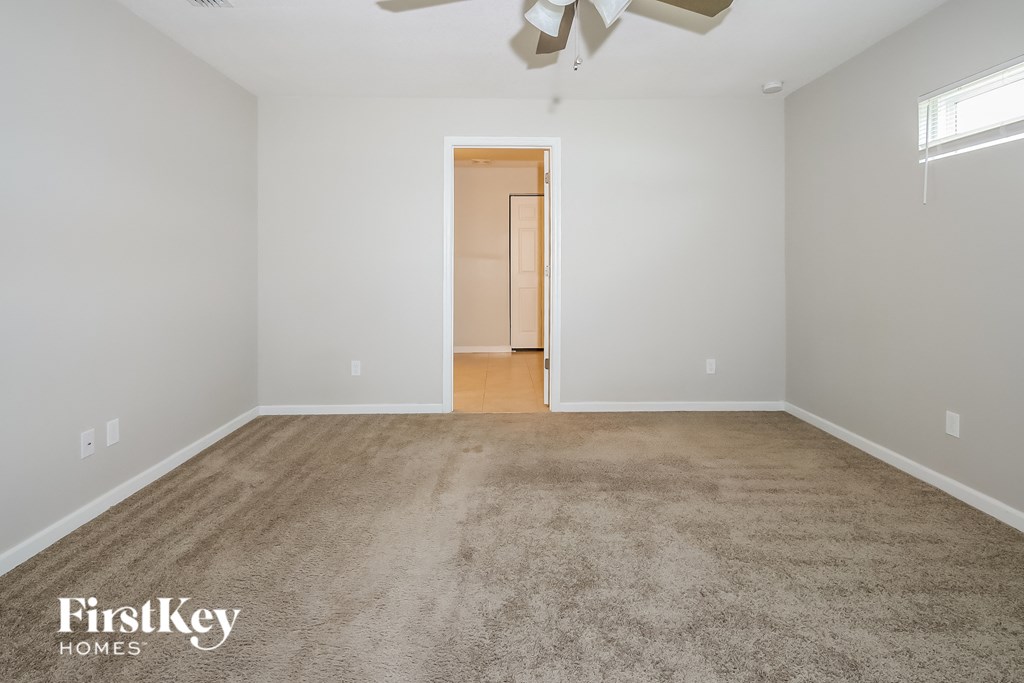 a empty living room with a carpeted floor and a ceiling fan