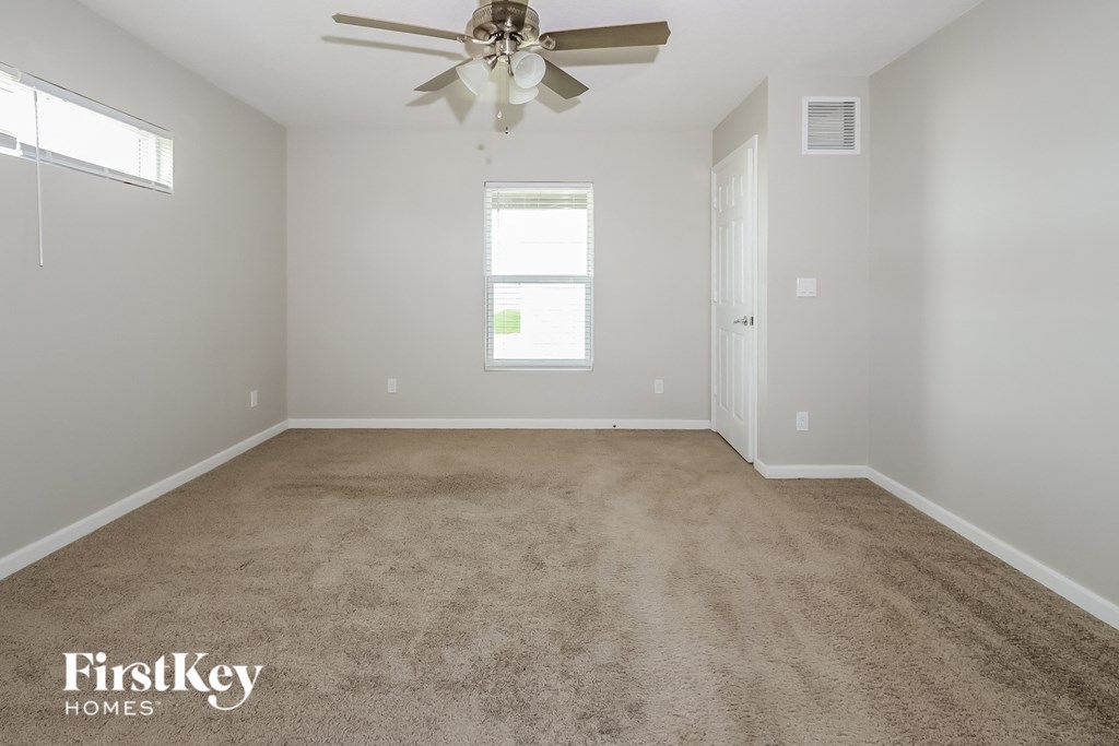 a carpeted room with a ceiling fan and a window
