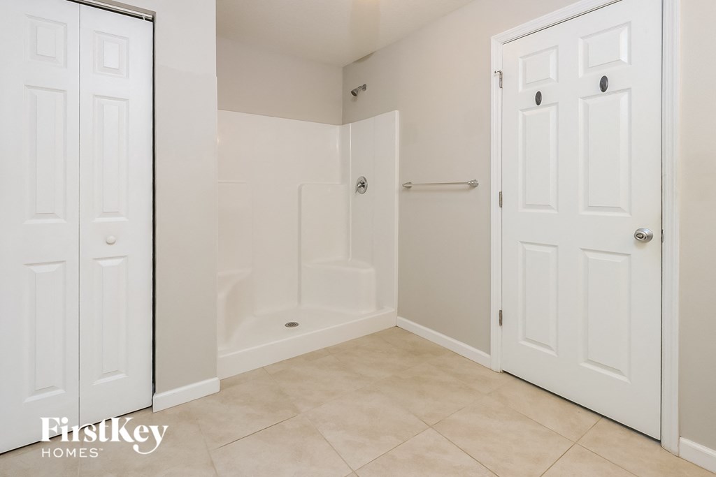 a bathroom with a shower and two closets and a tiled floor