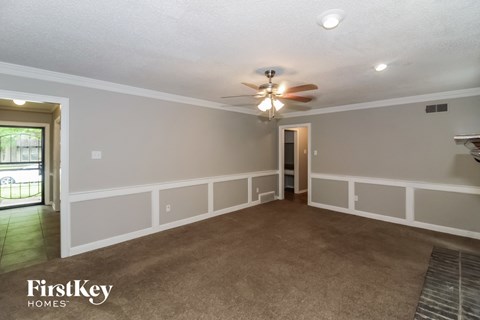 a living room with a ceiling fan and a carpet