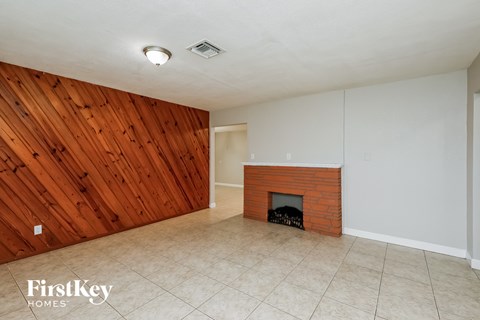 the living room has a brick fireplace and a wood accent wall