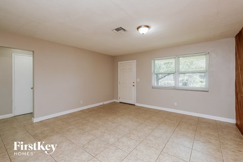 the living room of an empty house with a tile floor and a window