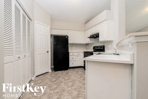 A kitchen with white cabinets and a black fridge.