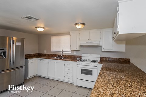 a kitchen with white cabinets and white appliances and granite counter tops