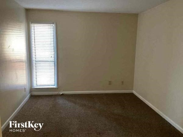 A room with a window and a carpeted floor.