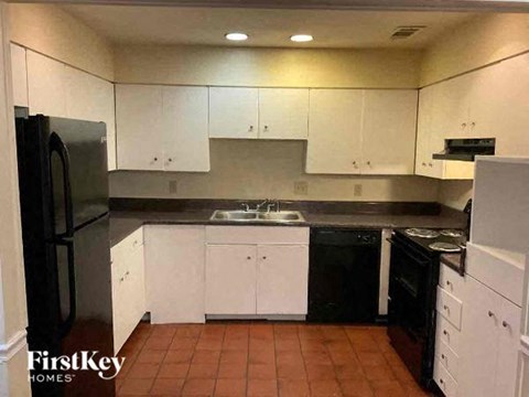 A kitchen with white cabinets and black appliances.